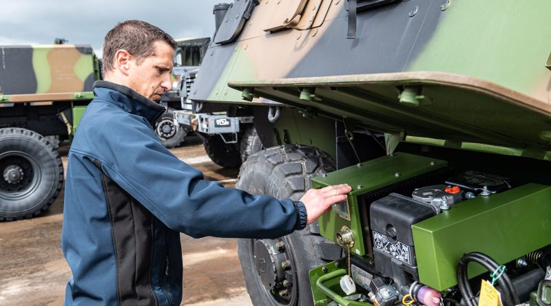 un homme devant une voiture de l'armée