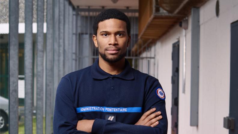 homme en tenue de surveillant pénitentiaire dans un couloir de prison