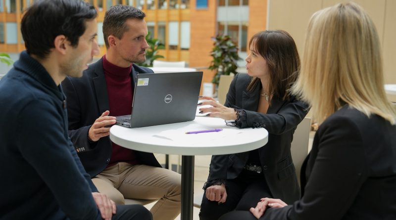 deux hommes et deux femmes assis autour d’une table et discutent pendant une réunion de travail informelle.