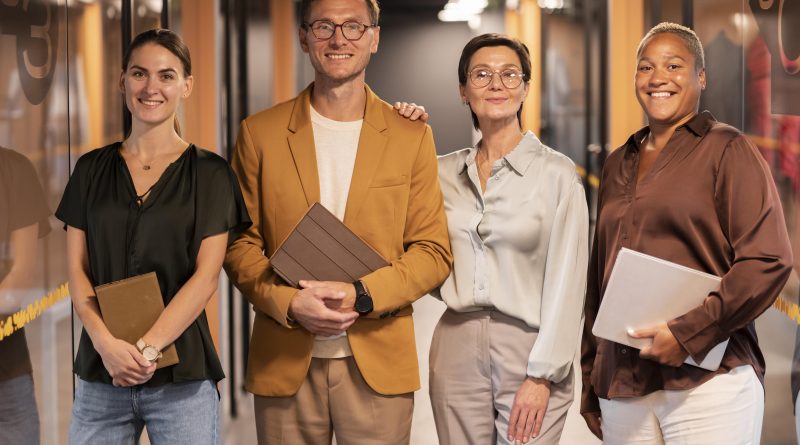 trois femmes et un homme d’âges différents et souriant sont regroupés dans un couloir coloré.