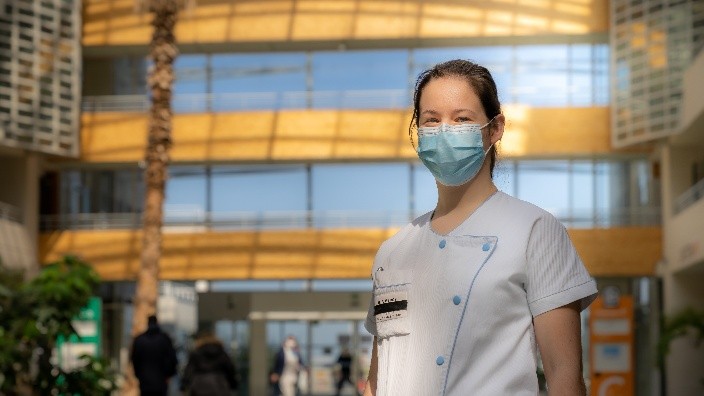 Professionnelle de santé masquée dans le hall d’un hôpital moderne.