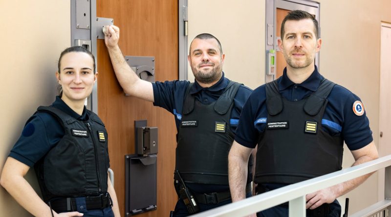 une femme et deux hommes en tenue de capitaine pénitentiaire dans la coursive d’une prison.